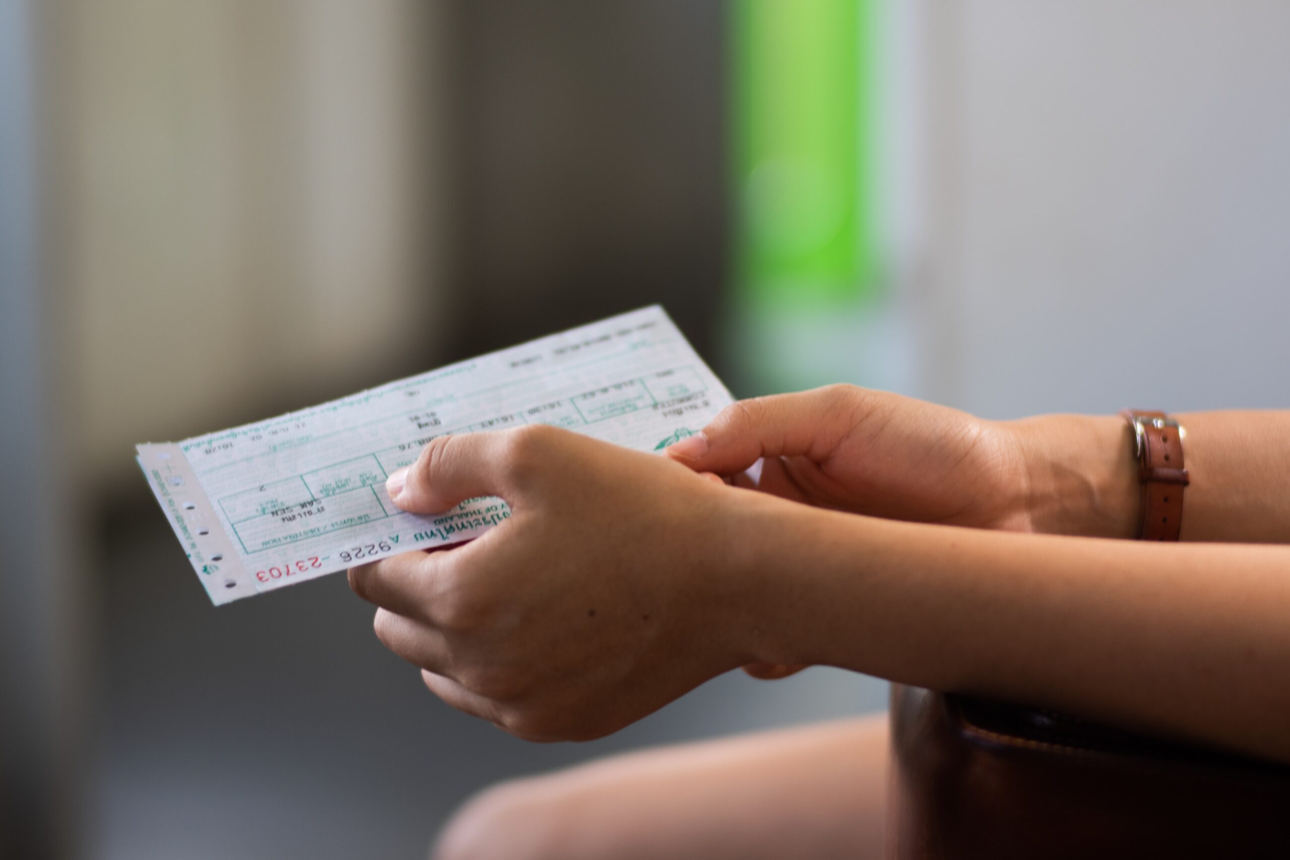 Close-up of hands holding a paper boarding pass, with a wristwatch visible